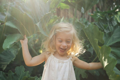 Portrait of little girl standing amidst plants, smiling 
