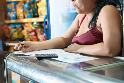 Worried woman reviewing her business statistics chart. writing with an eco-friendly cardboard pen 