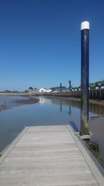 Pier on lake against clear blue sky