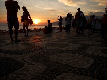 People standing on beach at sunset