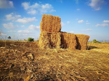 Hay bales on field against sky