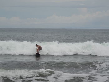 Man surfing in sea against sky