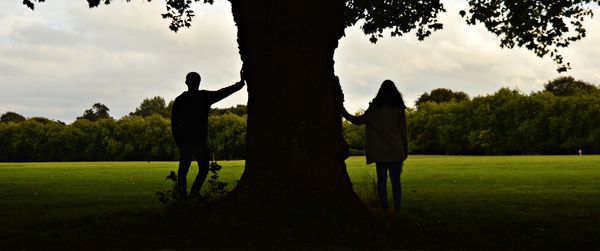 Silhouette people standing on field against sky