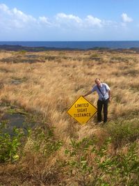 High angle view of man standing by signboard against sky