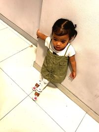 High angle view of girl standing by wall on floor at home