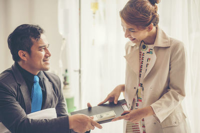 Businessman giving paper currency and file to colleague in hospital