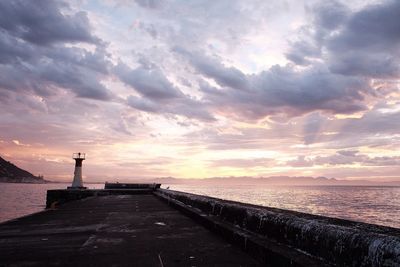 Scenic view of sea against cloudy sky at sunset