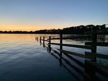 Pier on lake against clear sky during sunset