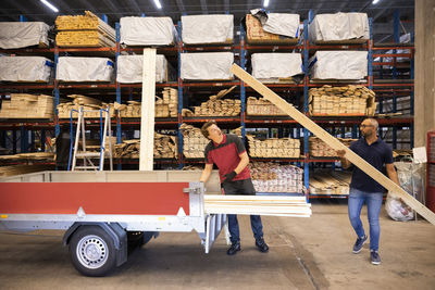 Male customer loading wooden plank in trailer at hardware store