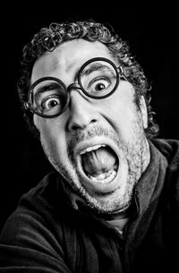 Portrait of man screaming against black background