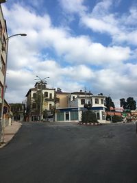 Street by buildings in town against sky