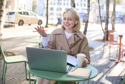 Young businesswoman using laptop while sitting on table