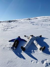 Low angle view of people skiing laying on snow covered landscape