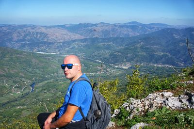 Man wearing sunglasses on mountain against sky