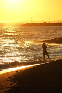 Silhouette man at beach against sky during sunset