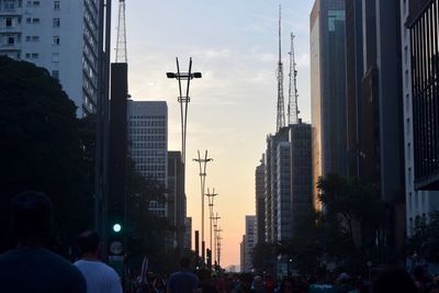 People on street amidst buildings in city against sky