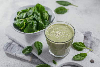 Glass of homemade healthy green smoothie with fresh baby spinach