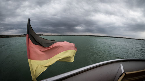 Flag on boat in sea against sky