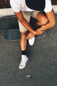 High angle view of man sitting with skateboard on street