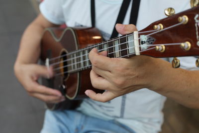 Midsection of man playing ukulele 