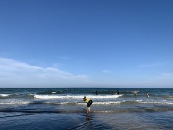 Smiling girl standing at shore against sky