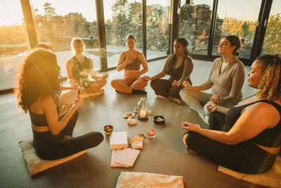 Multiracial female friends meditating together sitting cross-legged at retreat center