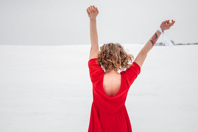 Rear view of woman with arms raised at beach