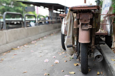 Black and white images of rusty old motorcycles parked on the side of the road.