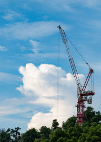Low angle view of cranes at construction site against sky