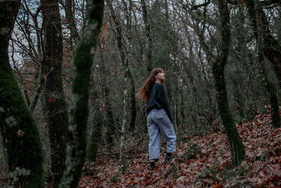 Low angle view of woman standing on autumn leaves in forest