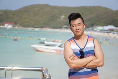 Portrait of man with arms crossed standing against sea