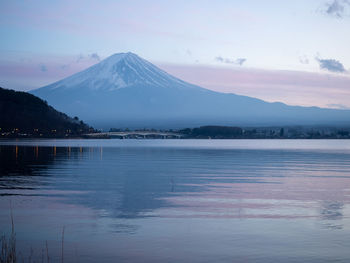 Scenic view of lake by snowcapped mountains against sky