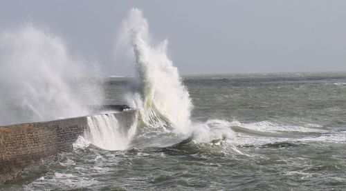 Waves splashing in sea against clear sky