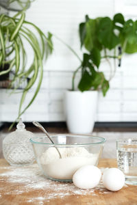 Vertical. pouring water into flour. making dough by female hands in white moden kitchen 