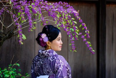 Portrait of woman standing against purple flowering plants