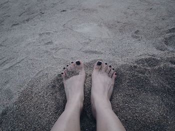 Low section of woman on sand at beach