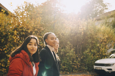 Portrait of smiling teenage girls in city during autumn
