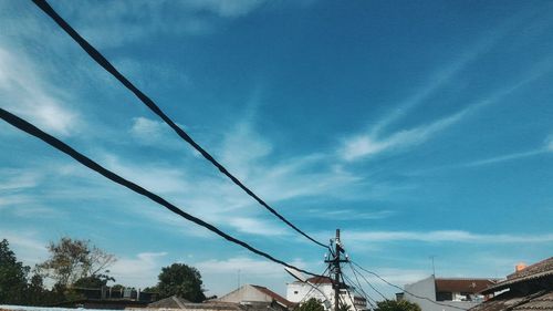 Low angle view of electricity pylon against blue sky