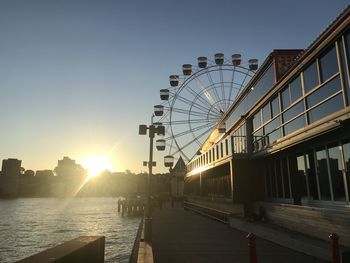 Ferris wheel in city against clear sky during sunset