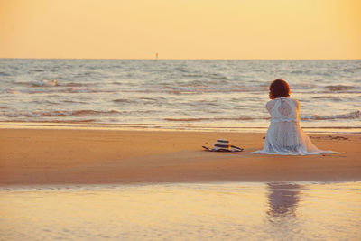 Rear view of woman on beach during sunset