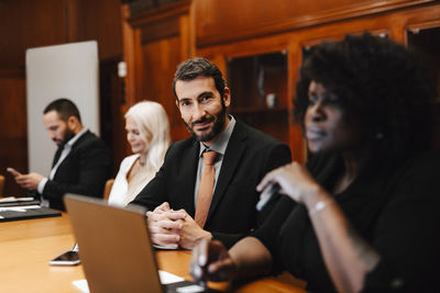 Portrait of confident businessman sitting with colleagues in board room
