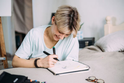 Smiling woman doing drawing at home