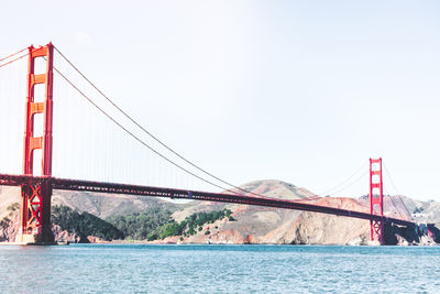 Suspension bridge over sea against clear sky