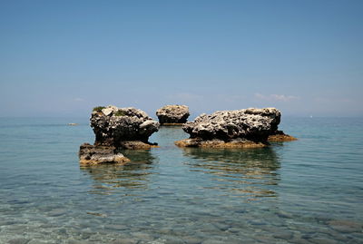 Rocks in sea against clear sky