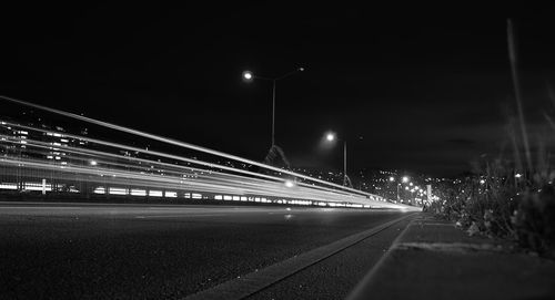 Light trails on road against clear sky at night