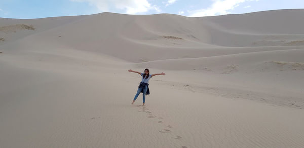 Full length of woman with arms outstretched standing at desert
