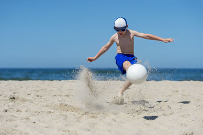 Boy playing volleyball against sea