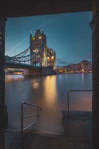 Illuminated bridge over river in city at night