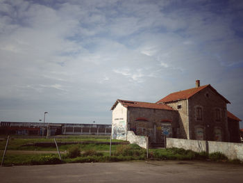 Empty road by buildings against sky