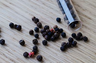 High angle view of black peppercorns on table fallen from test tube